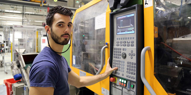 An employee standing in front of a plastic injection machine